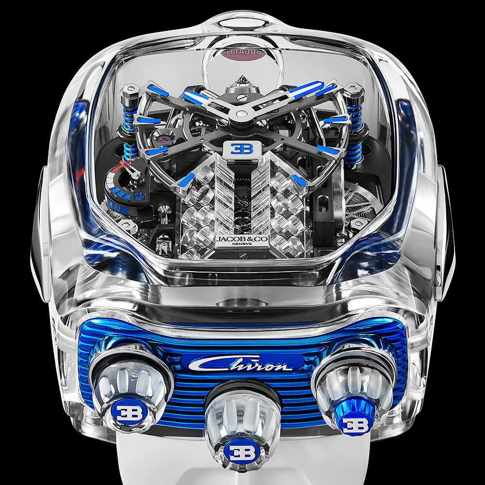 Back view of a high-end watch with a transparent case and red strap, showing the movement and gears through the crystal.
