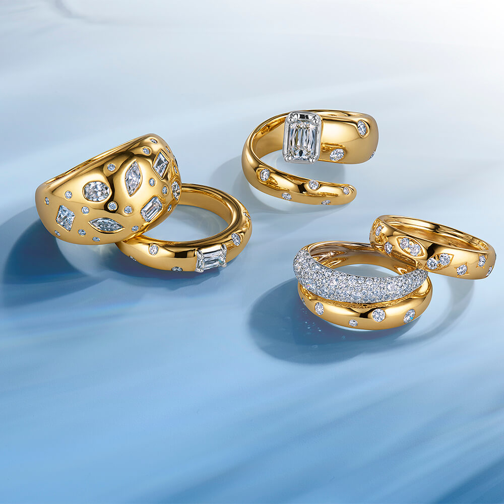 Set of gold rings with diamonds arranged on a light blue surface with soft shadows.